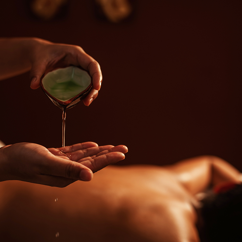 Masseur pouring aroma oil on hand, for massage on back of custom